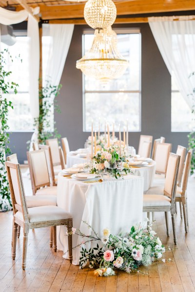 Empty dining room table setting flowers chairs chandelier hanging