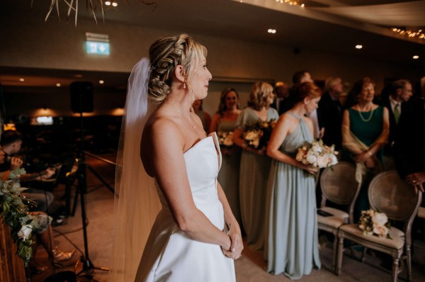 Bride stands with veil waiting for bride