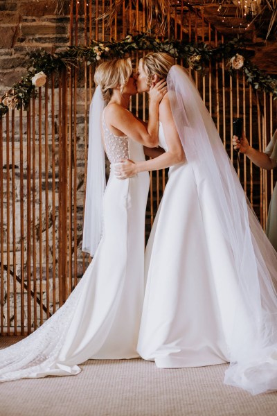 The brides kiss in front of audience