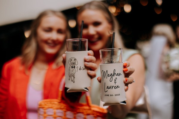 Guests holding up glasses one has a little dog sketch on it