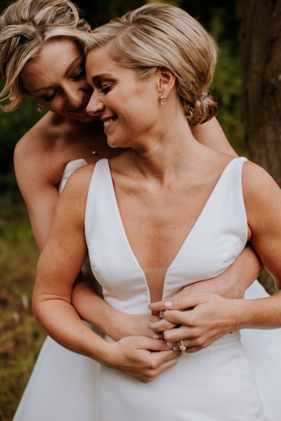 Brides hug embrace arms around waist they smile