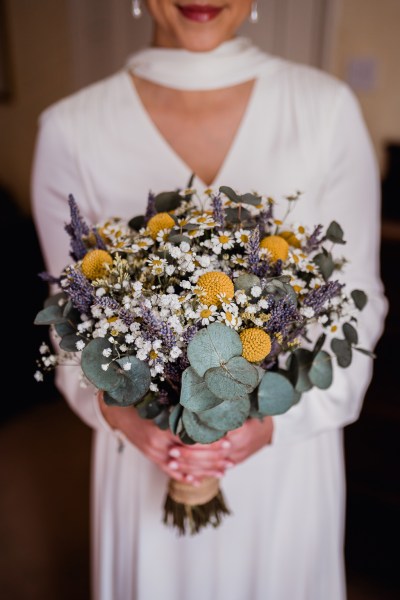 Bride stands holding flowers bouquet