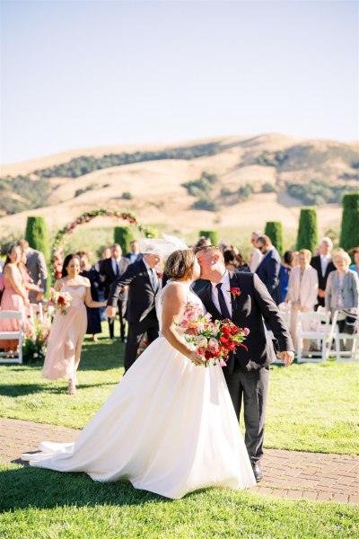 Bride and groom kiss on the grass after ceremony