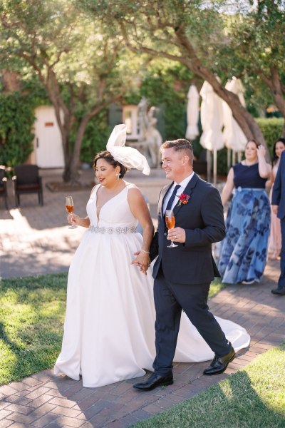 Bride and groom walking hand in hand holding cocktail