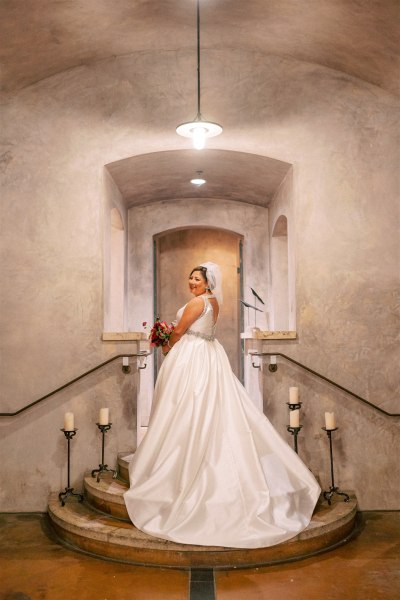 Bride stands on stairs candles surround her