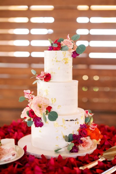 Wedding cake white covered in flowers on top of red roses