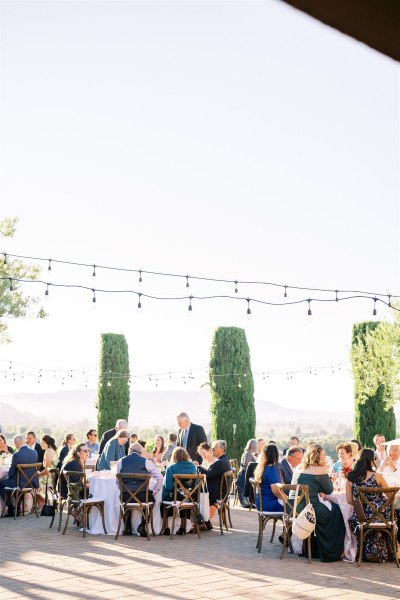 Atmosphere shot of guests seated in garden chatting fairy lights above