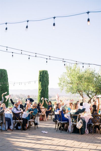 Atmosphere shot of guests seated in garden chatting fairy lights above