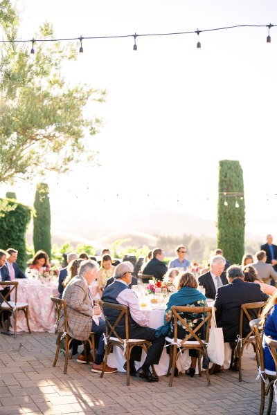 Guests seated outside fairy lights above dining room