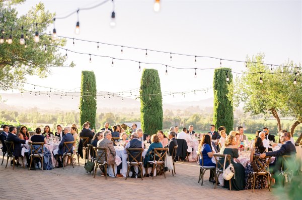 Guests seated outside fairy lights above dining room