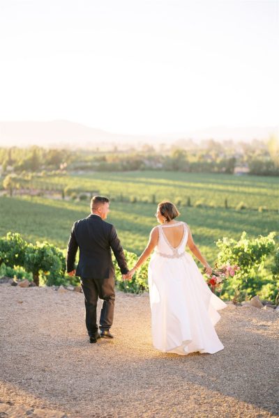 Bride and groom walking towards grass away from camera