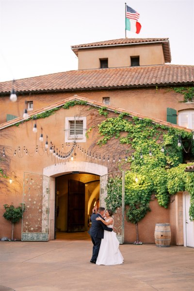 Bride and groom hug and dance in the courtyard in front of wedding venue