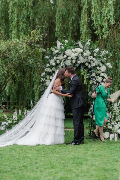 bride and groom kiss as they are pronounced husband and wife at the top of the alter