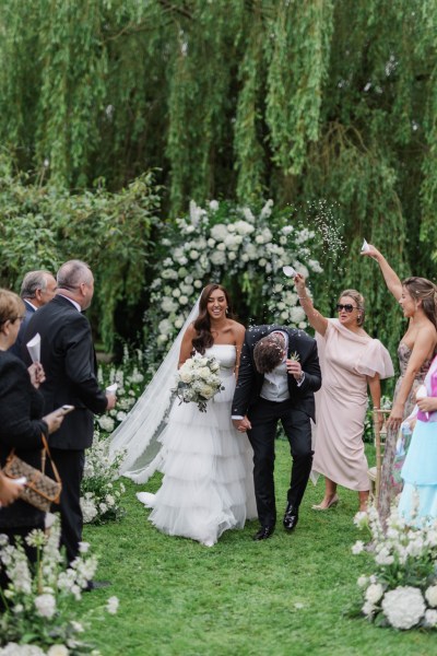 bride and groom exit the ceremony confetti being thrown over couple by guests