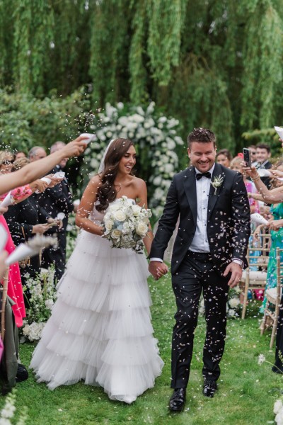 bride and groom exit the ceremony confetti being thrown over couple by guests