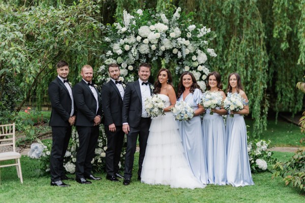 bride and groom bridesmaids groomsmen pose on the grass together