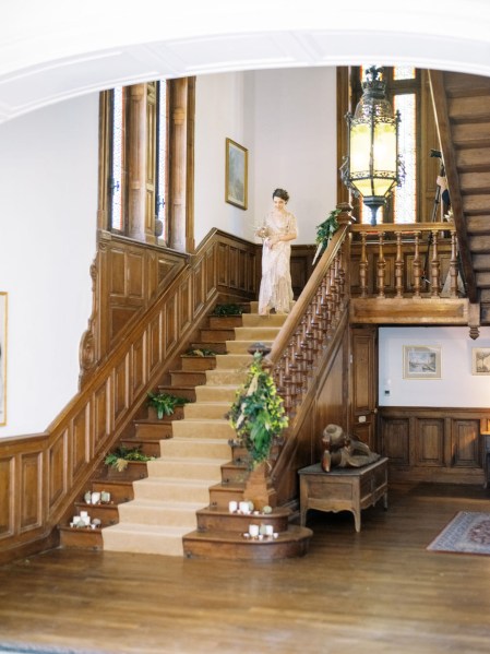 Bride stands at the top of the wooden staircase