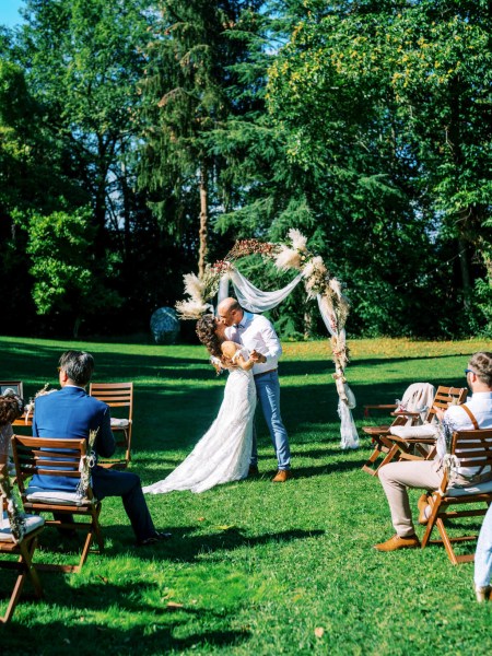 bride and groom with celebrant at top of alter setting the couple kiss in front of guests