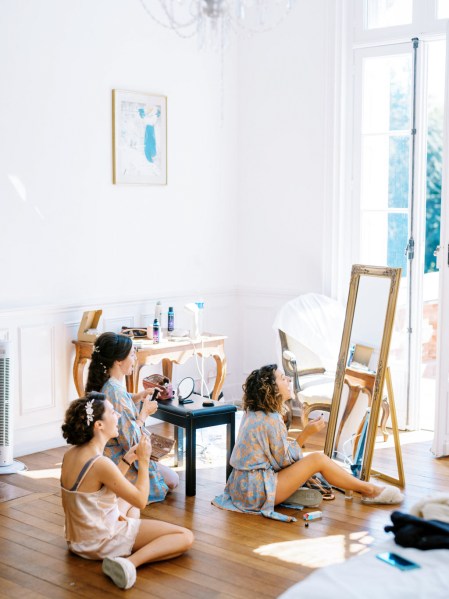 Bride and bridesmaids getting ready in room mirror