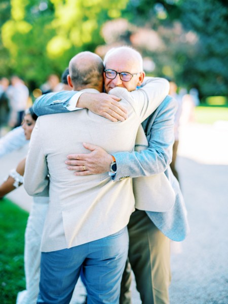 Two men hug in suits on pathway