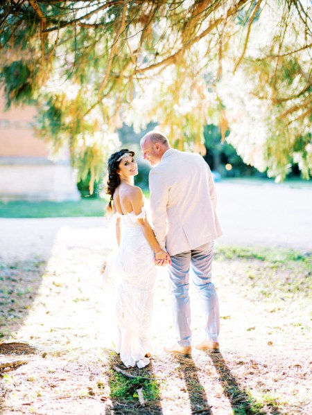 Bride and groom standing in forest setting sun is shining