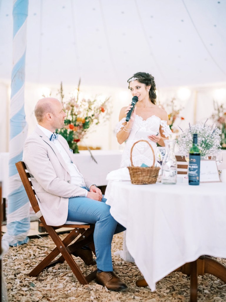 Bride gives speech as groom watches