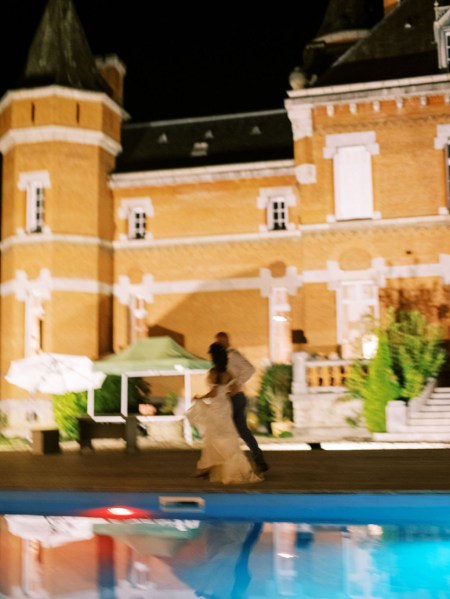 Nighttime shot of blue pool and wedding castle exterior