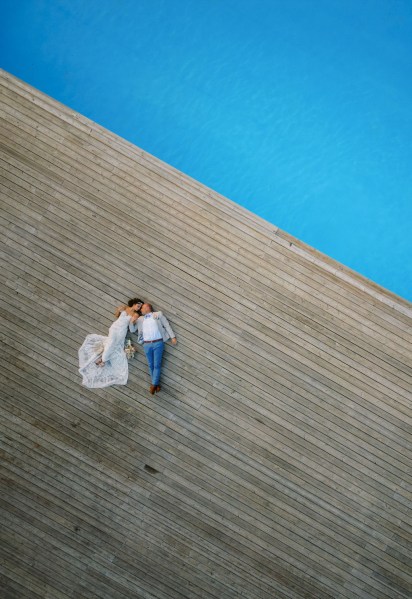 Blue pool view and bride and groom lying flat drone shot footage