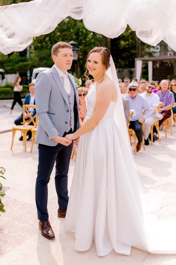 bride and groom hold hands at the alter