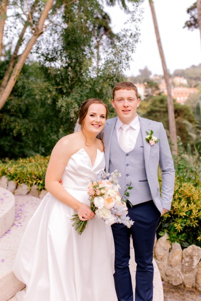 bride and groom in garden she holds bouquet