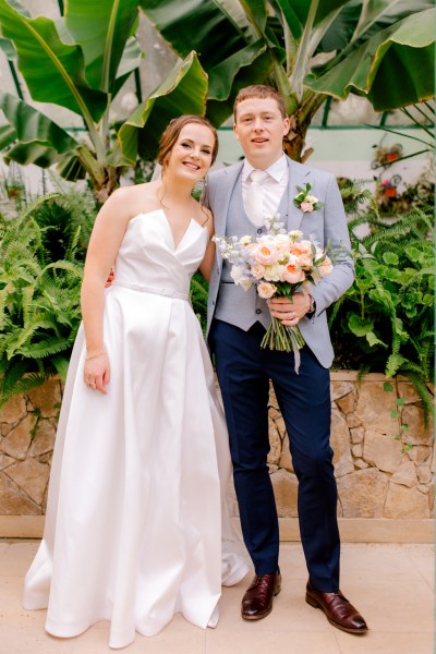 bride and groom in garden she holds bouquet