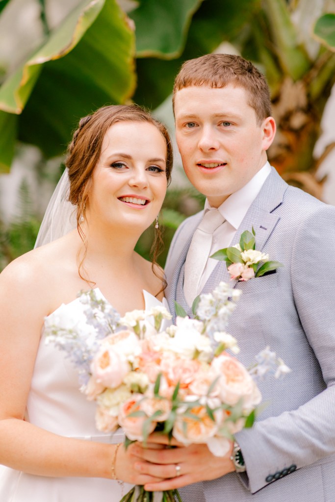 bride and groom in garden she holds bouquet