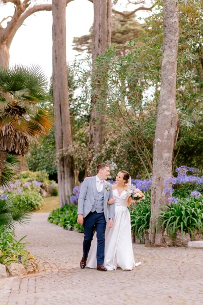 bride and groom walking in forest garden setting on pathway hand in hand