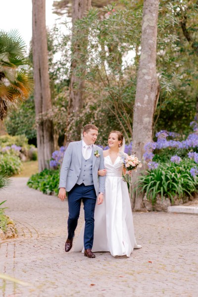 bride and groom walking in forest garden setting on pathway hand in hand