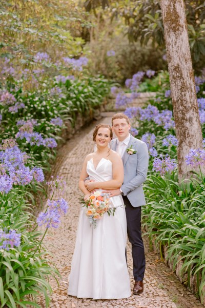 bride and groom walking in forest garden setting on pathway arm around brides waist