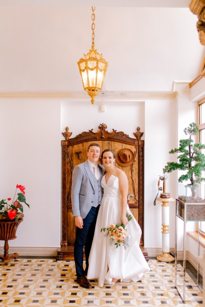 bride and groom stand in room together arms around each other