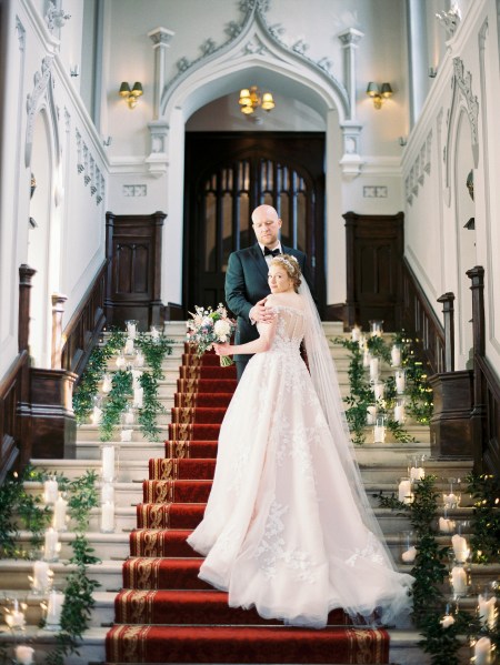 bride and groom stand on red carpet lights candles lanterns placed on either side