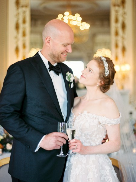 bride and groom face each other smiling cheers with glasses of champagne prosecco