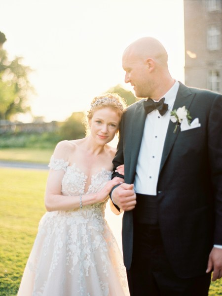 sunsets as bride leans her head on grooms arm she smiles