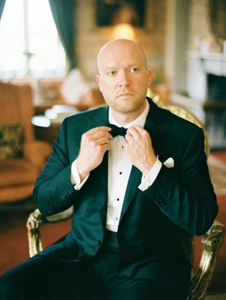 groom fixes up his bowtie tuxedo