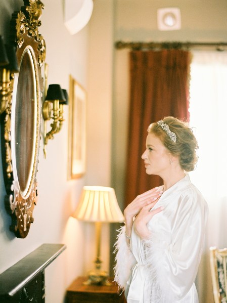 bride fixes her hair and hair accessory in mirror