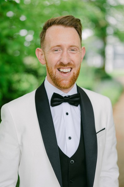 Groom in bowtie stands and poses in garden