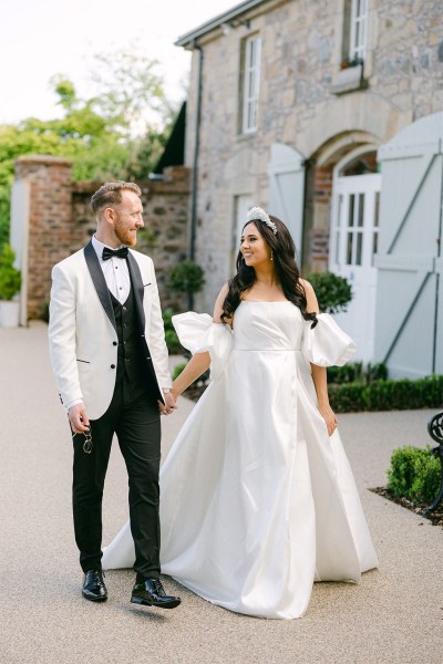 Bride and groom walk hand in hand in the courtyard