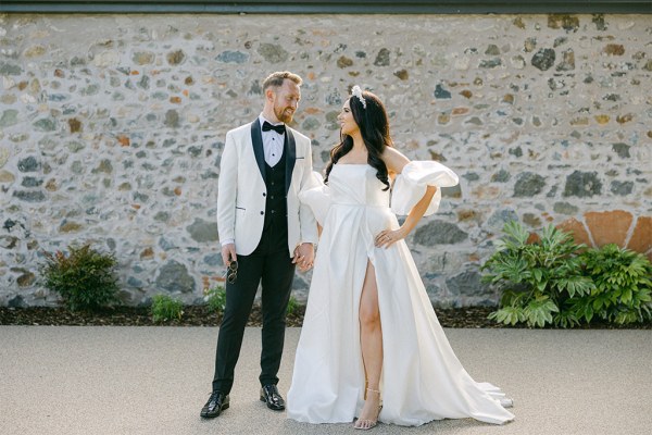 Bride and groom look at each other smiling in courtyard to venue