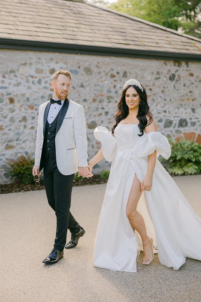 Bride and groom walk hand in hand in the courtyard