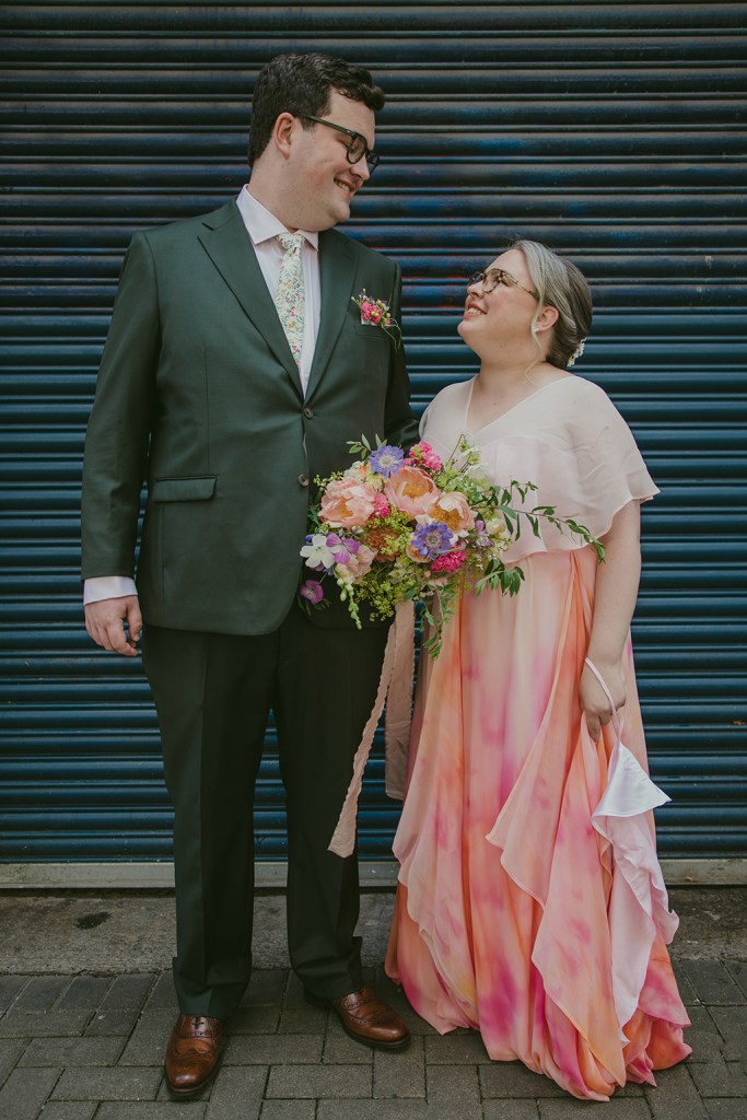 bride and groom in front of garage shop shutter door and look at each other