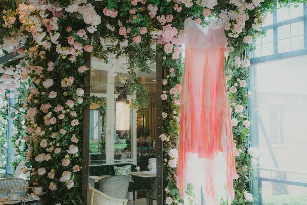 orange coloured bridal gown dress hanging up in front of pink flowers