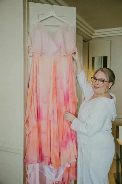 orange coloured bridal gown dress hanging up in front of pink flowers