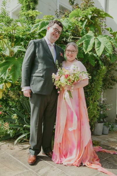 bride and groom stand in garden setting