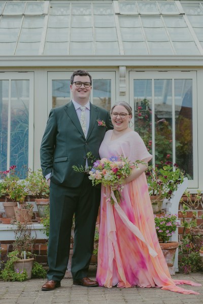 bride and groom beside greenhouse to garden